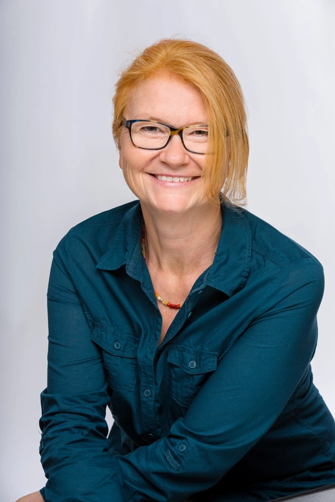 Maria Richter lächelnd mit schwarzer Brille und zusammengebundenen Haaren